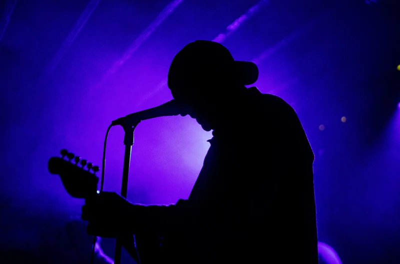 Singer silhouetted under purple lighting