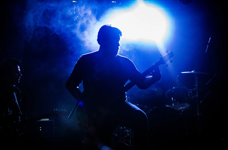 Musician silhouetted against blue stage lighting